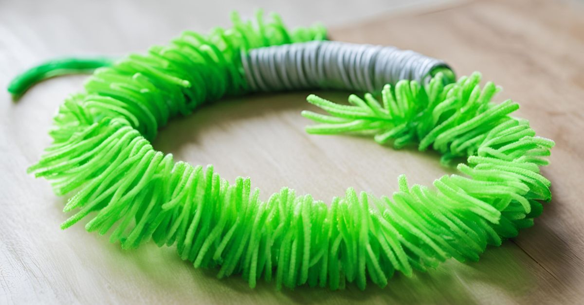 Close-up of a bright green DIY pipe cleaner spring cat toy, with the ends safely folded over